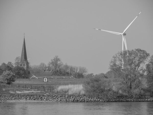A split-screen image showing a wind turbine farm on one side and a coal-fired power plant on the other, symbolizing the transition from fossil fuels to renewable energy and the challenges of balancing energy needs with environmental concerns.